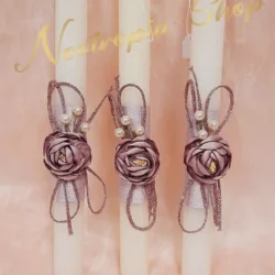 Μια αριστοκρατική χειροποίητη λαμπάδα σε εκρού χρώμα, διακοσμημένη με ένα εντυπωσιακό υφασμάτινο λουλούδι στην απόχρωση του σάπιου μήλου. Οι χρυσές λεπτομέρειες με τις κομψές πέρλες και η λαμπερή τρέσα συνθέτουν ένα μοναδικό αποτέλεσμα για μια απόλυτα σικ εμφάνιση στην Ανάσταση.